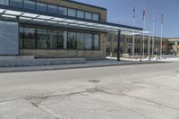 the side of the building features an enclosed glass wall and columns, along with some flags