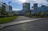 a walkway leading to some buildings and grass near some trees in the foreground and a building that is in the background