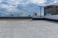 a large concrete parking lot next to tall buildings on a cloudy day with some blue skies