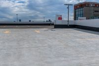 a large concrete parking lot next to tall buildings on a cloudy day with some blue skies