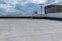 a large concrete parking lot next to tall buildings on a cloudy day with some blue skies