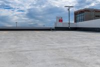 a large concrete parking lot next to tall buildings on a cloudy day with some blue skies