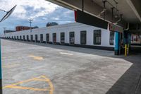 a bus is parked on the side of a long building while waiting for passengers to board