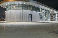 a circular building at night with traffic going by by it and people on the sidewalk