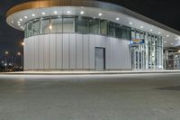 a circular building at night with traffic going by by it and people on the sidewalk