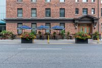 some tables with blue umbrellas and flower pots with flowers on them and yellow poles