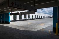 an open parking garage area for parked cars and a blue sky with clouds in the background