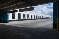 an open parking garage area for parked cars and a blue sky with clouds in the background