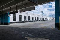 an open parking garage area for parked cars and a blue sky with clouds in the background