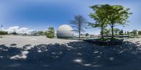 a spherical fish eye lens shot of a building by the water and trees and a boat in front