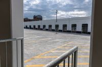 an open door with an empty parking lot and clouds in the background of a building