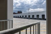 an open door with an empty parking lot and clouds in the background of a building