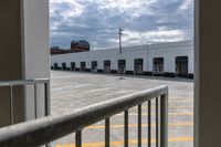 an open door with an empty parking lot and clouds in the background of a building