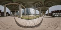 a fish eye lens shot of a curved walkway with many buildings in the background from one perspective to the other