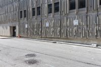 the side of an office building with a few signs on it and concrete around a road