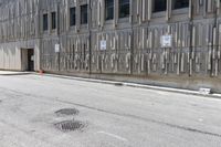 the side of an office building with a few signs on it and concrete around a road