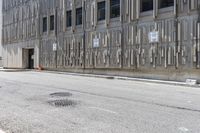 the side of an office building with a few signs on it and concrete around a road