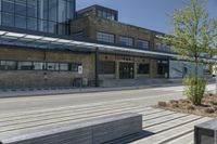 a park bench is near a road and building along with windows to let in sun