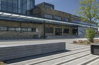 a park bench is near a road and building along with windows to let in sun