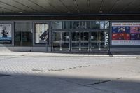 a person sitting at the bench in front of a mall that is empty of people