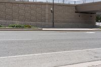 a stop sign with white painted lines on the pavement in front of a bridge and building