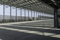 a walkway over looking a fence in an industrial setting with the sun filtering through the glass