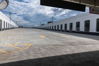 the empty parking lot with a white building on top of it and a yellow doted logo