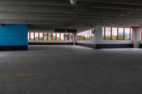 an empty parking garage that has red and white walls and large windows in it with a blue door