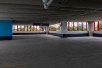 an empty parking garage that has red and white walls and large windows in it with a blue door