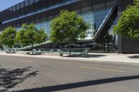 an industrial building with a curved walkway between trees and a sidewalk in front of it