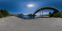 fish eye view of the walkway bridge over a river surrounded by trees and other green space