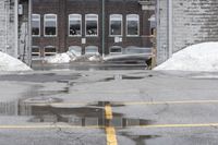 the empty parking lot has only snow on the ground in front of an old brick factory