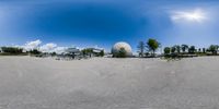 a fisheye photo of a beach and water frontage and some buildings in the background