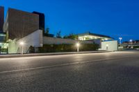 a street in front of some buildings at night with lights on the side of it