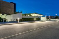 a street in front of some buildings at night with lights on the side of it