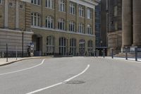 a city street with buildings and pedestrians walking around the curbs down the road next to each other