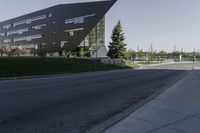 an empty street in front of a school building on a clear day with sun shining