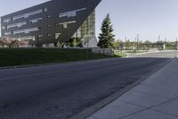 an empty street in front of a school building on a clear day with sun shining