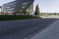 an empty street in front of a school building on a clear day with sun shining