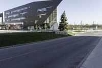 an empty street in front of a school building on a clear day with sun shining