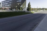 an empty street in front of a school building on a clear day with sun shining