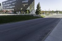 an empty street in front of a school building on a clear day with sun shining