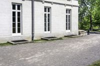 the building is a stone with three large windows on it and benches in front of it