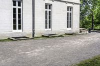 the building is a stone with three large windows on it and benches in front of it