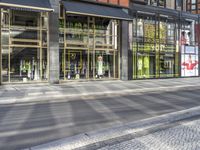 a man on a bike walking down the street beside store windows and onlookers