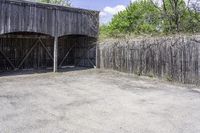 a wooden barn with some plants on the roof and outside wall next to a fence