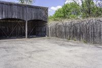 a wooden barn with some plants on the roof and outside wall next to a fence