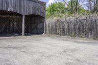 a wooden barn with some plants on the roof and outside wall next to a fence