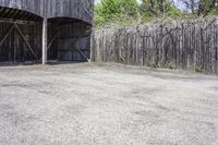 a wooden barn with some plants on the roof and outside wall next to a fence