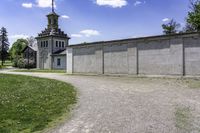 an empty concrete building near a grassy field in front of a large church tower and clock tower